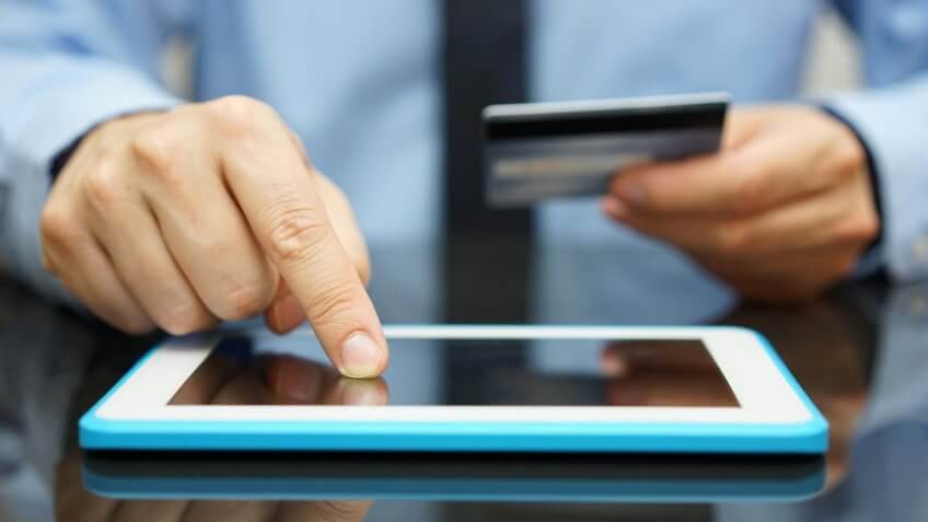 businessman is buying goods on tablet computer with credit card.