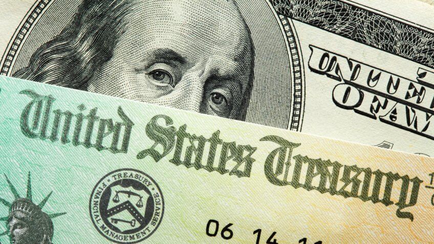 The portrait of Benjamin Franklin on the one hundred dollar bill peering from behind a check issued by the U.