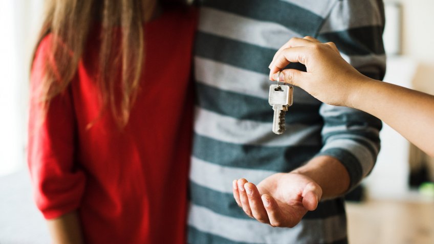 person hanging keys to man's hand standing next to woman