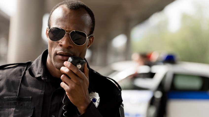 african american police officer talking by walkie-talkie radio set.