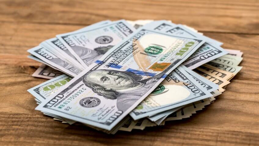 Heap of dollar banknotes on wooden background.