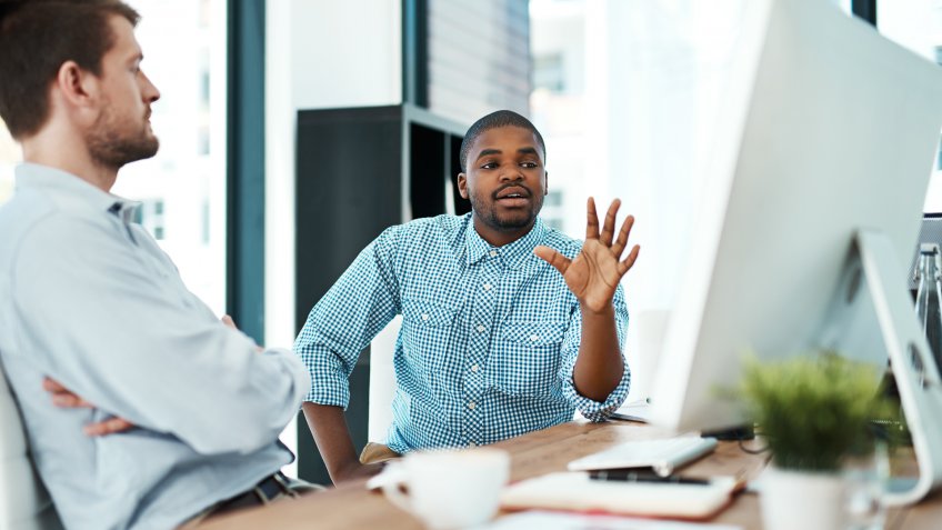 Cropped shot of two designers discussing something on a computer.