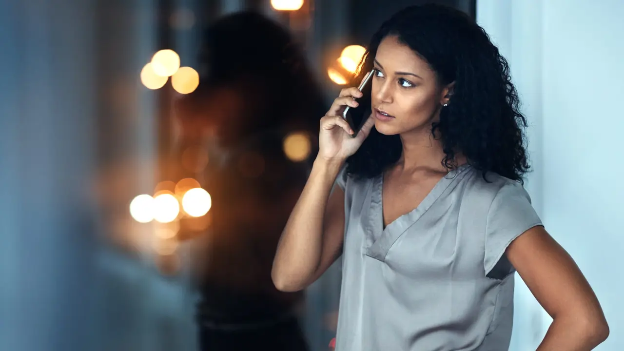 Shot of a young businesswoman talking on a mobile phone during a late night at work.