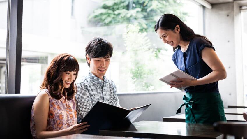 Attractive looking young adults are eating out in a restaurant and ordering from menu.