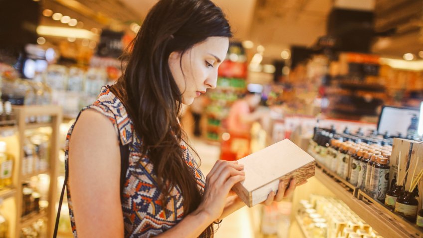 Image of a young brunette woman, browsing through the shelves of a Bangkok shopping mall, looking for natural cosmetics.