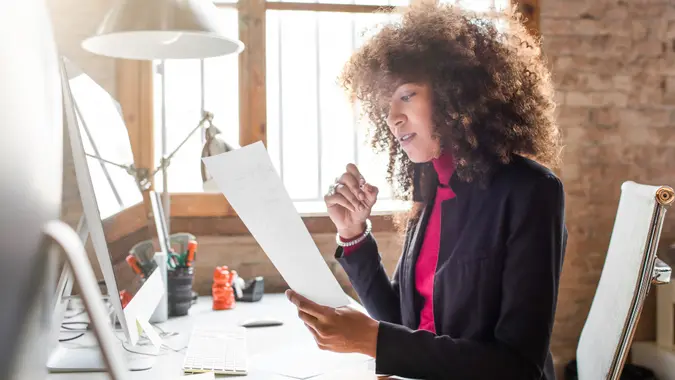 Concentrated businesswoman working in the office, she's revising some documents.