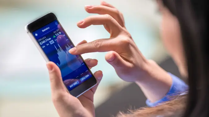 Close-up photo of a woman using a smart phone app to track her financial portfolio.