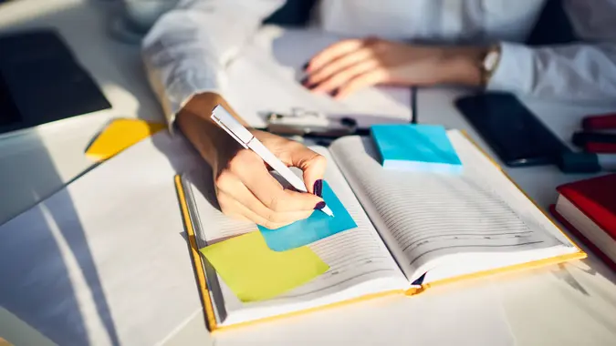 Cropped image of creative female secretary creating planning for executive noting important meeting and events organizing work of busy boss while sitting at working place in coworking office.