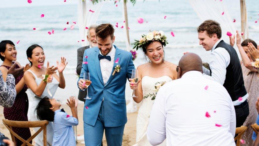 Cheerful multiracial newlyweds at beach wedding ceremony