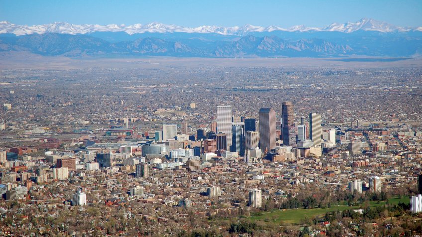 Aerial photo of downtown Denver, Colorado with the Rocky Mountains in the background.
