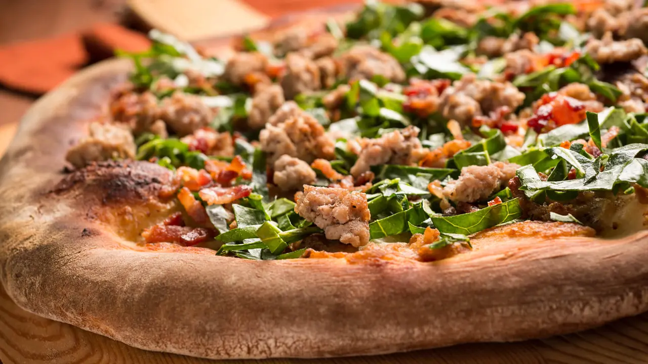 Gourmet pizza with sausage and spinach.