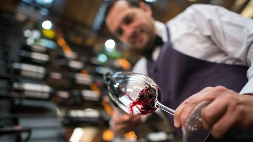 Sommelier pouring a glass of wine at a cellar.