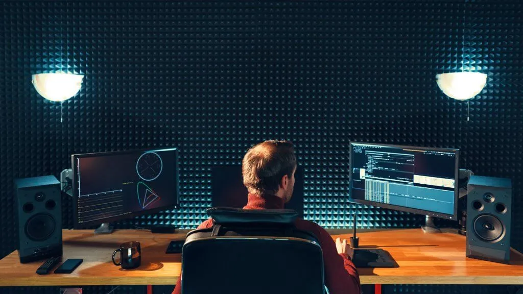 video editor at a desk with two monitors and speakers