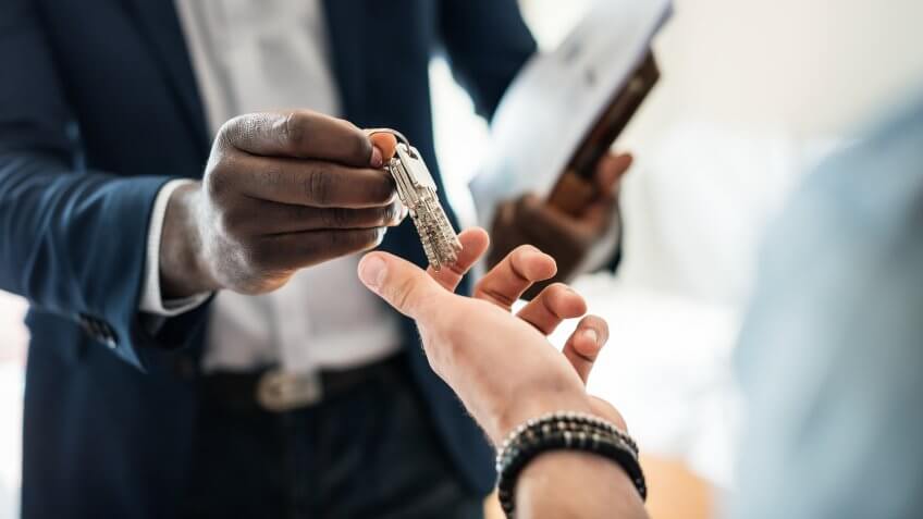 Real estate agent handing the house key to a client.