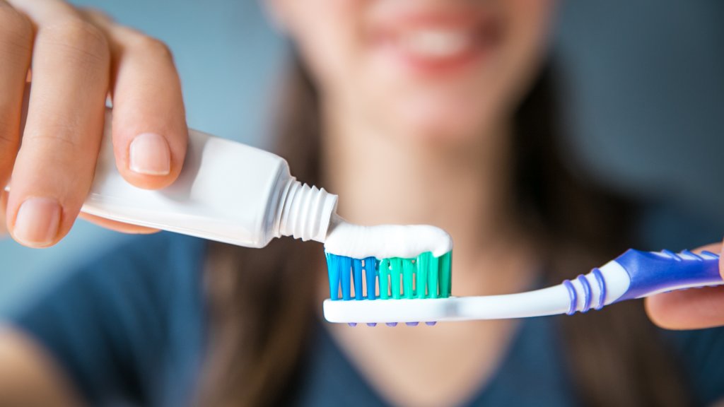 applying toothpaste to toothbrush to brush teeth