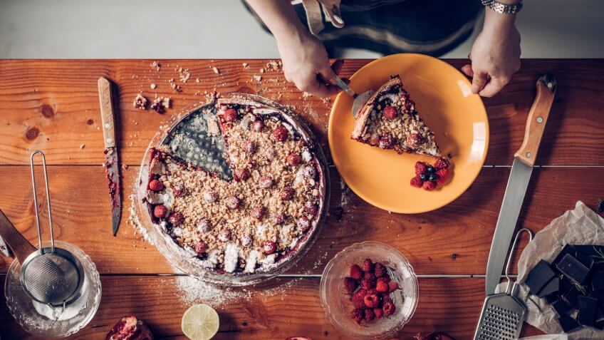 Young woman cutting the slice of cake.