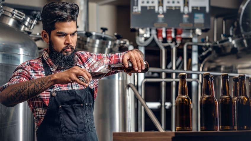brewer pouring out beer into a glass cup