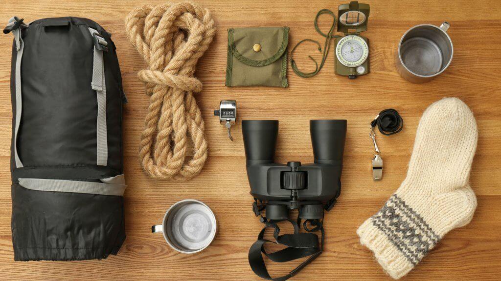 Flat lay composition with sleeping bag and camping equipment on wooden background - Image.