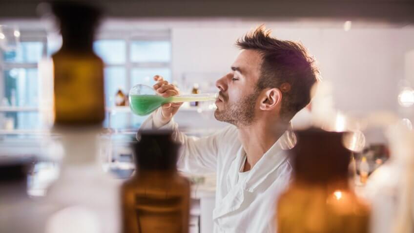 Young scientist drinking toxic substance from a beaker in laboratory.