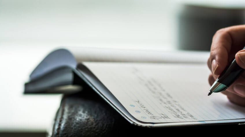 An author scribbles notes in a notebook with a smartpen - Image.