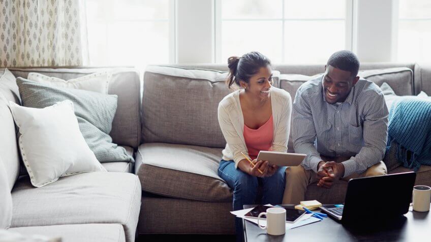 Shot of a young couple going through paperwork together on the sofa at home.