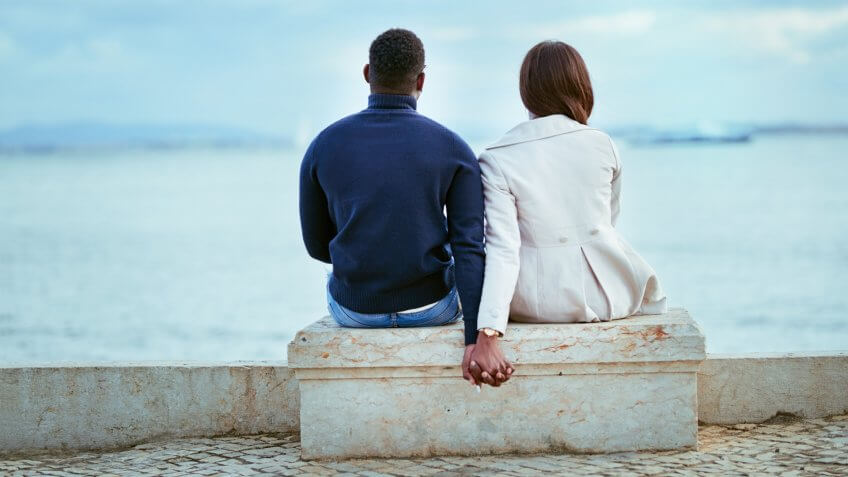 Rearview shot of a young couple looking at the view of the sea outdoors.