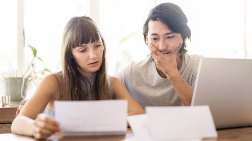 Tensed young couple reading document at home.