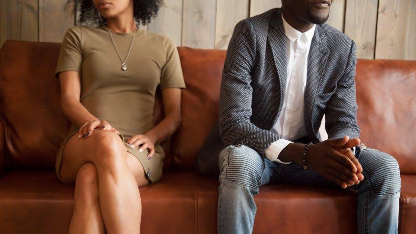 African american unhappy couple sitting on couch after quarrel fight thinking of break up or divorce, black upset man and woman not talking having conflict, bad relationships concept, close up view.