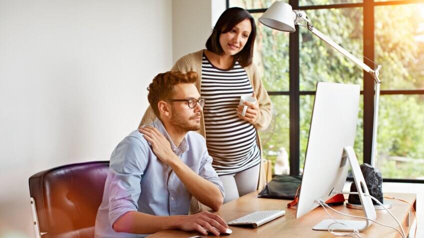 Shot of an expecting couple working together in their home office.