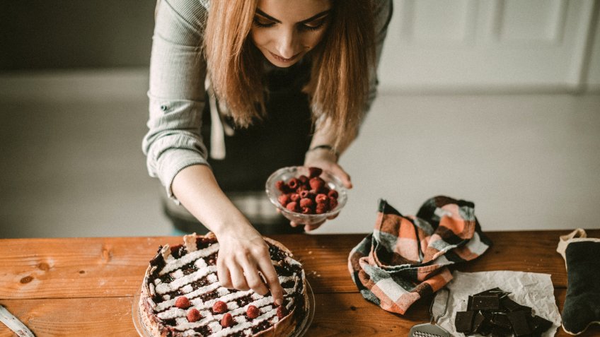 Young woman decorating cake.