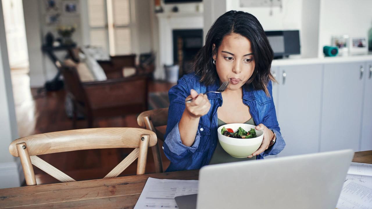 woman eating salad while managing finances
