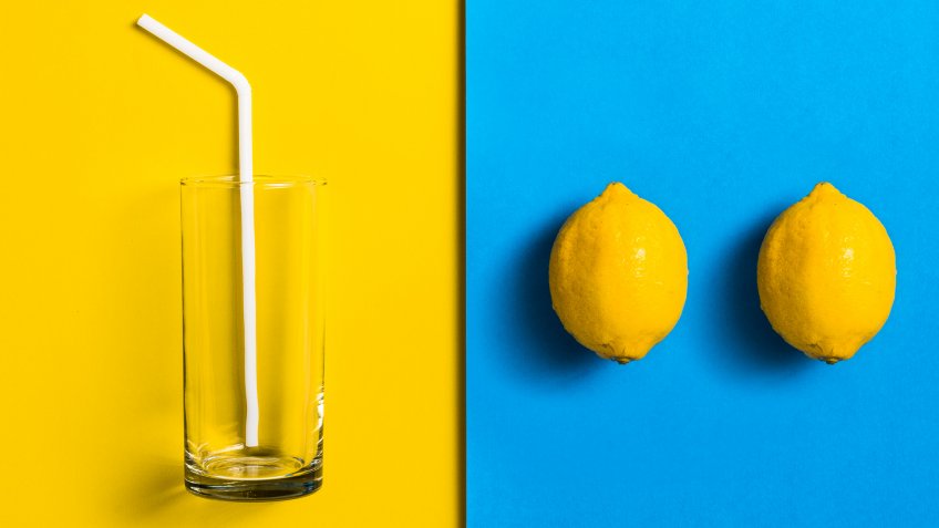 empty glass with two lemons on yellow and blue background