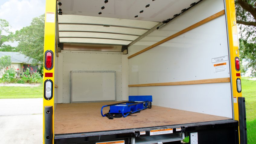 Empty yellow moving truck with blue dolly in back.