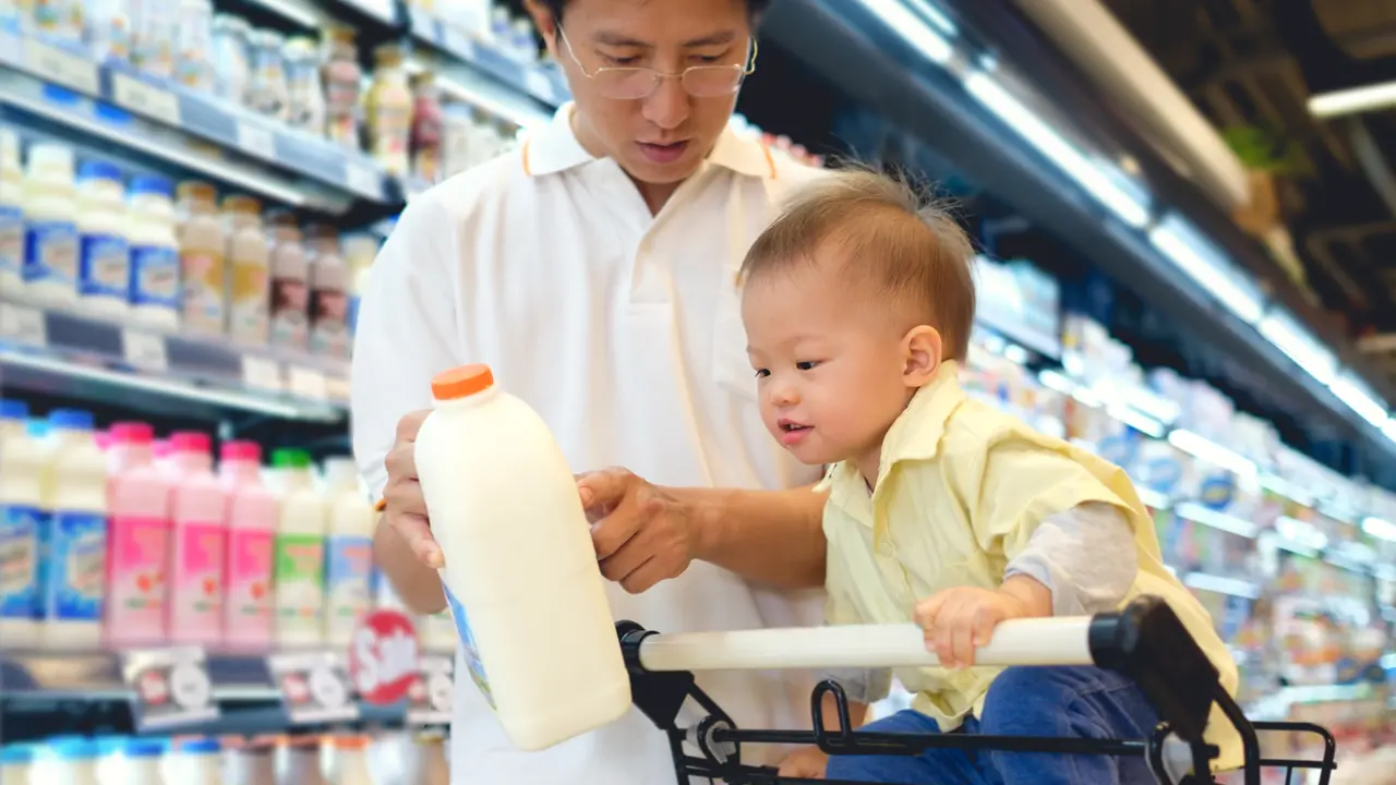 father and baby son looking at milk jug