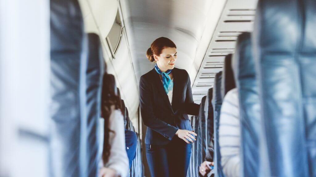 flight attendant standing in the aisle of an airplane