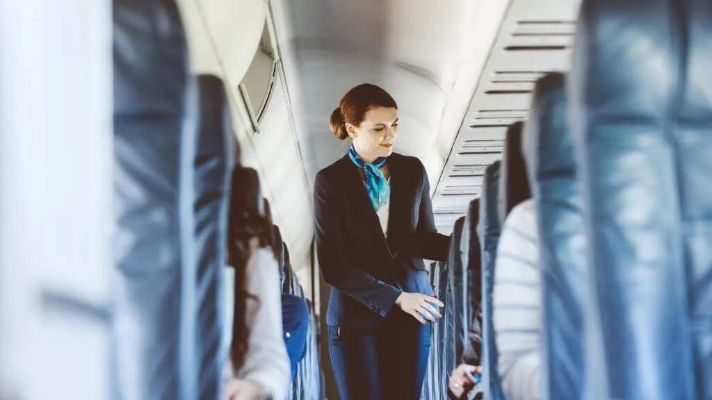 flight attendant standing in the aisle of an airplane