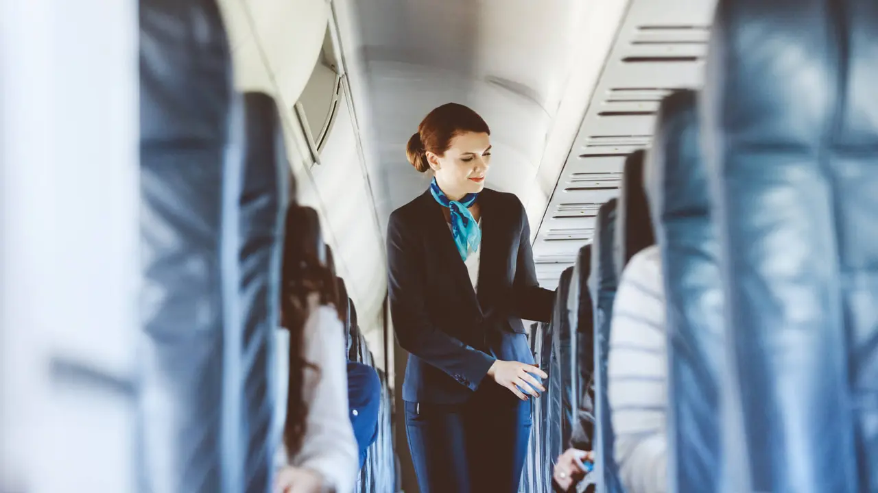 flight attendant standing in the aisle of an airplane