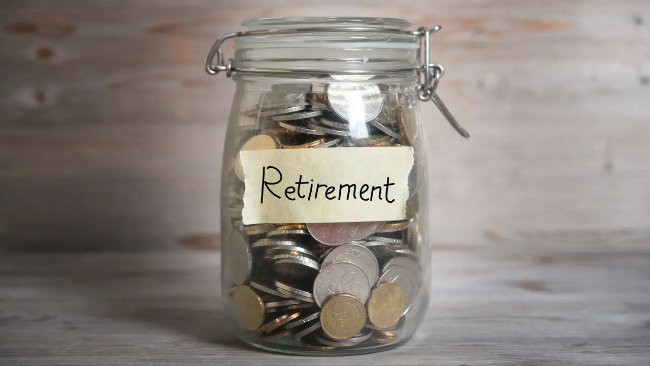Coins in glass jar with retirement label, financial concept.