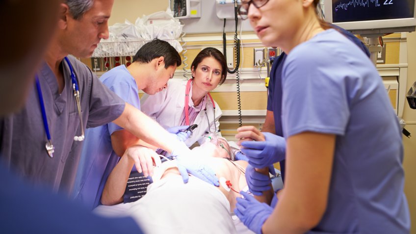 Hard Working Medical Team Working On Patient In Emergency Room.