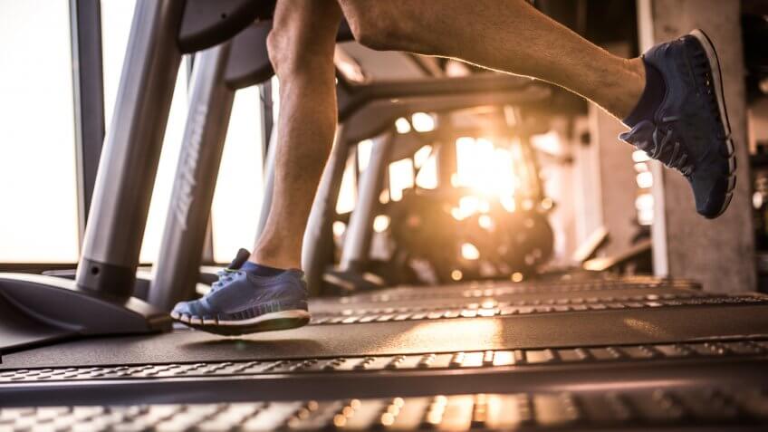 Unrecognizable sportsman jogging on treadmill in a gym.