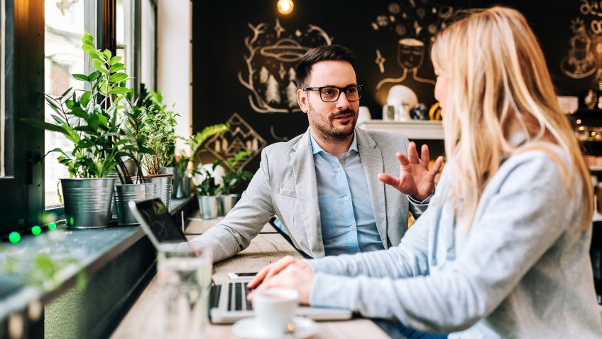 Handsome man talking to a young blonde woman at the cafe.