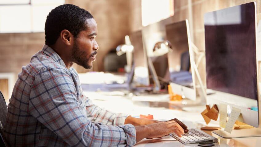 man typing on computer in office