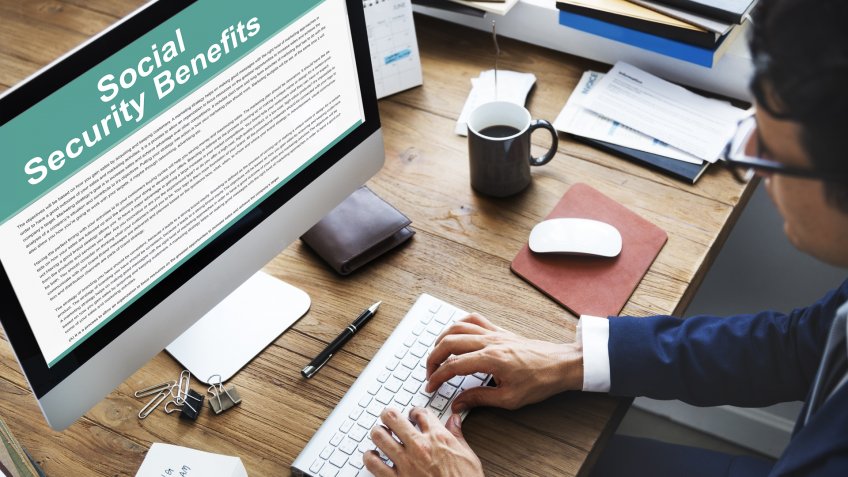 man typing on computer with Social Security benefits on screen