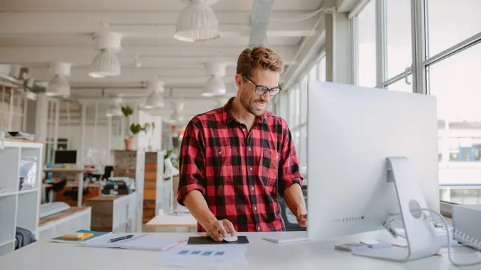 Shot of happy young man working on desktop computer in modern workplace.