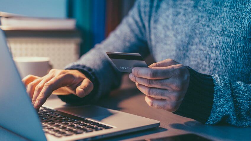 man with credit card in front of laptop
