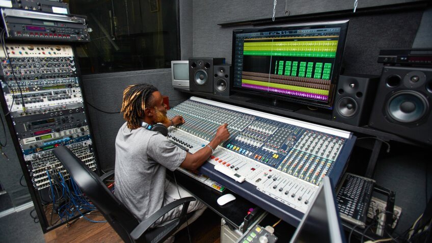 Deejay sitting in front of stereo system in studio.