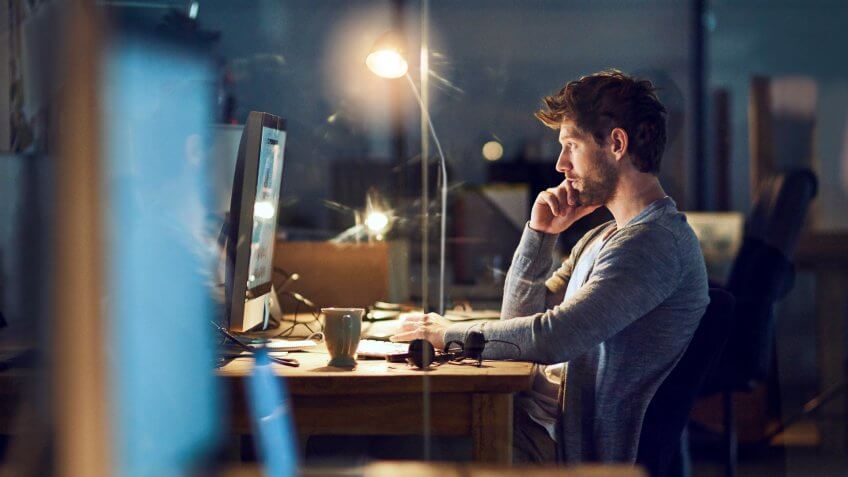 young designer working late on a computer in an office.