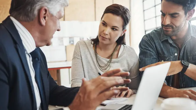 Shot of a young married couple consulting with their financial advisor in his office.