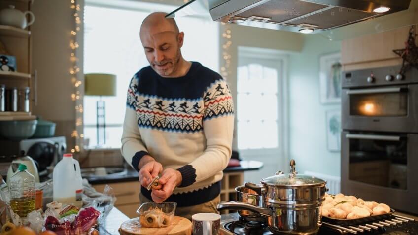 One mature man is preparing a christmas dinner in the kitchen of his home.