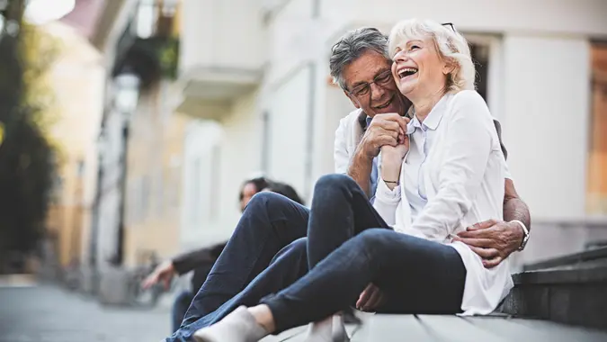 Happy senior couple sitting on a bench in city center.